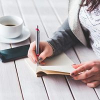 编辑部主笔在台灯下翻看纸质校样，手边摊着写满批注的稿纸，暖橙色光线里神情专注